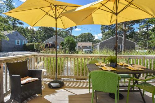 een patio met een tafel en 2 parasols bij Cottage w Private Association Pool in Wellfleet