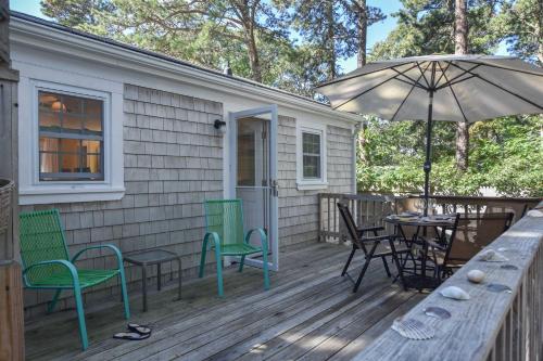 a deck with a table and chairs and an umbrella at Cottage w Private Association Pool in Wellfleet