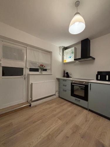a kitchen with white cabinets and a stove top oven at Cosy- Casa in Luton
