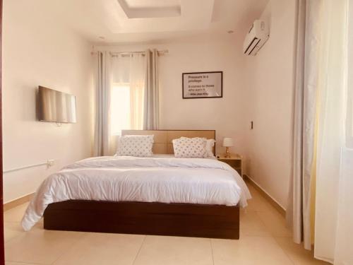 a bedroom with a large bed with white sheets and a window at Simplistic Ambience At The Lekki Peninsula, Lagos in Mama