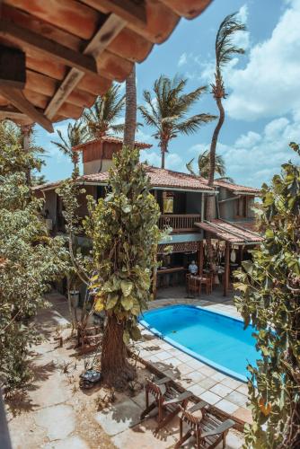 a house with a swimming pool and palm trees at Pousada Fortal Jeri in Jericoacoara