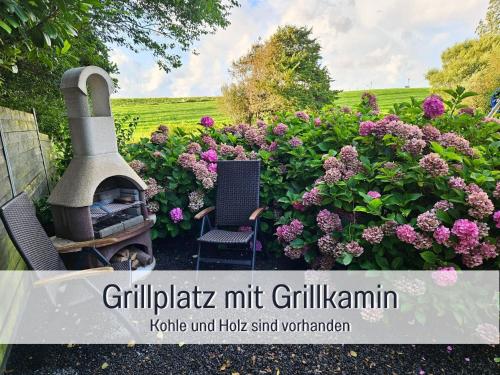 a garden with flowers and a wood fired grill at Ferienwohnung KUMM RIN - Oase an der Nordsee in Carolinensiel