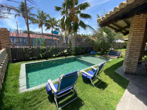 Dos sillas y una piscina en un patio. en Casa pé-na-areia c/ piscina e serviço incluído em Japaratinga, en Japaratinga