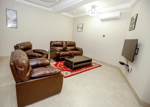 DPE Apartments في كوماسي: غرفة معيشة مع كرسيين جلديين وتلفزيون