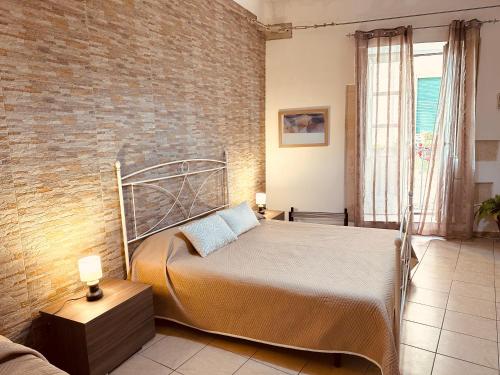 ein Schlafzimmer mit einem Bett und einer Ziegelwand in der Unterkunft Ortilì in Syrakus