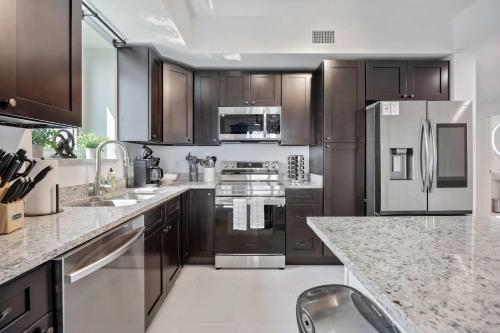 a kitchen with wooden cabinets and stainless steel appliances at RIVER FLY IN The Cocoa Island Horizon View RFI 3BR KQQ City in Audubon