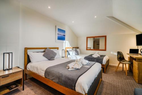 a hotel room with two beds with a dog laying on the bed at The Victoria Inn in Truro