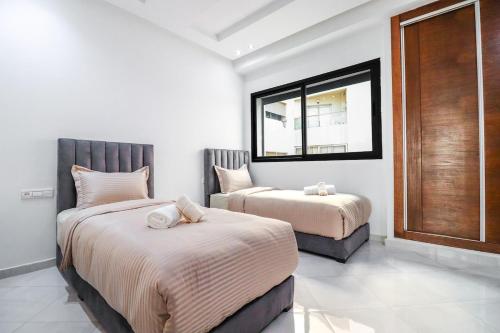 a bedroom with two beds and a window at L'Etincelle 2 chambres à deux pas de la Gare in Kenitra