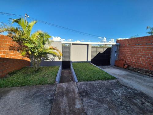 una casa con una palmera y una pared de ladrillo en Descanso Guazú, en Posadas