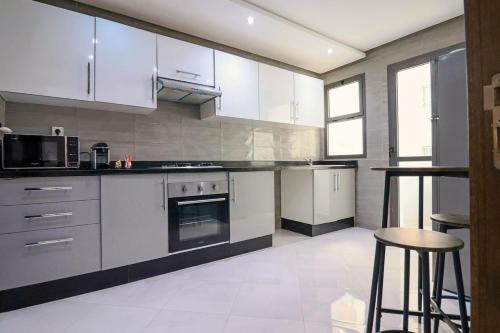 a kitchen with white cabinets and a stove top oven at L'Etincelle 2 chambres à deux pas de la Gare in Kenitra
