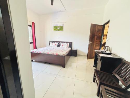 Un dormitorio con una cama y una silla en una habitación. en Aroha home stay, en Pālampur