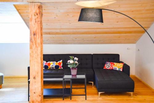 a living room with a black couch and a table at Spitzing Lodge Ferienwohnungen - Wanderparadies in den Bergen in Spitzingsee