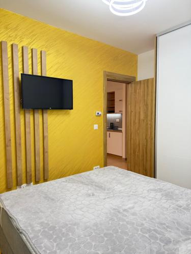 a bedroom with a flat screen tv on a yellow wall at Prestige Forest Resort Zlatibor Wellness & Spa in Zlatibor