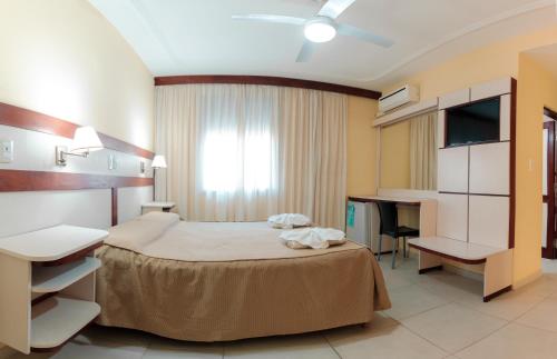 a bedroom with a bed and a desk and a television at Grand Hotel Principado in Termas de Río Hondo