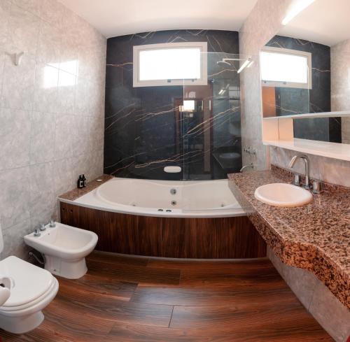 a bathroom with a tub and a toilet and a sink at Grand Hotel Principado in Termas de Río Hondo