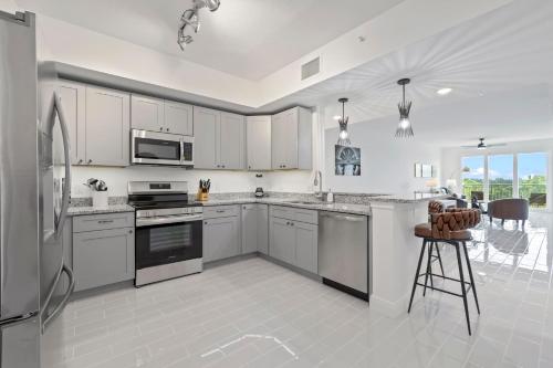 Luxury River Front Secluded Condo w Resort Amenities RFI 909 في Audubon: مطبخ بدولاب بيضاء وأجهزة وطاولة