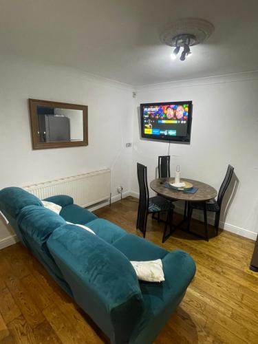 a living room with a blue couch and a table at Lovely 4 bed house with patio & bbq in Slades Green