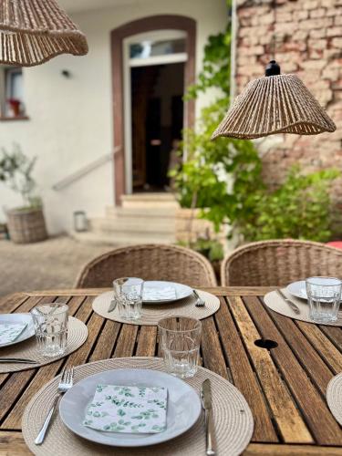 a wooden table with plates and glasses and umbrellas at Das Winzereck - 4 Sterne Ferienhaus in der Südpfalz in Ranschbach