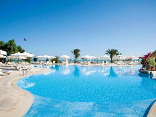 a large swimming pool with chairs and umbrellas at Movenpick Resort & Spa El Gouna in Hurghada
