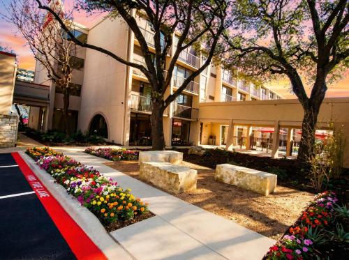 a building with flowers in front of a building at Ramada by Wyndham Austin South in Austin