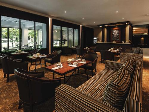 a restaurant with tables and chairs and windows at Movenpick Suriwongse Hotel Chiang Mai in Chiang Mai