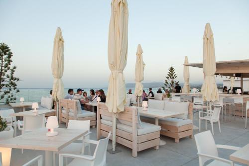 a restaurant with white tables and chairs and the ocean at Georgioupolis Beach Hotel in Georgioupolis