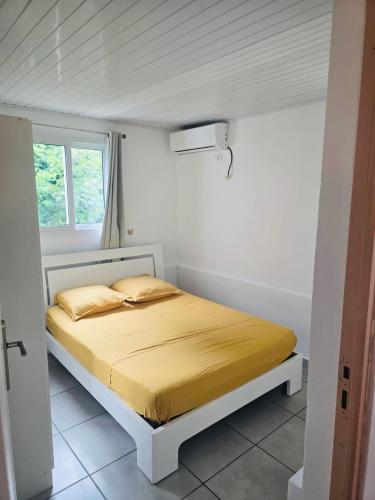 a white bedroom with a bed with yellow sheets at Chez Pascal in Terre-de-Haut