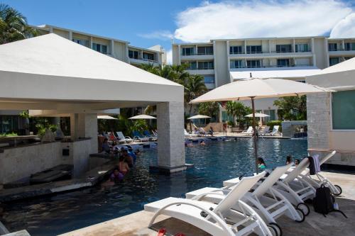 a pool with white lounge chairs and a hotel at BeachAccess HotelZone 3705 in Cancún