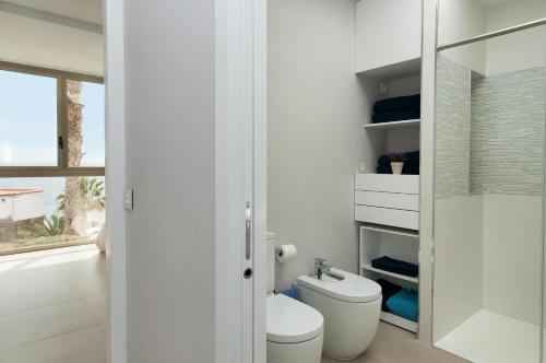 ein weißes Bad mit einem WC und einem Fenster in der Unterkunft Apartment Playa del Aguila NE/IM in Playa del Aguila