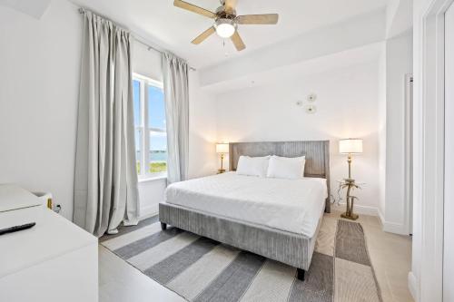 RIVER FLY-IN Luxury Condo w Views & Amenities RFI-1003 في Audubon: غرفة نوم بيضاء مع سرير ومروحة سقف