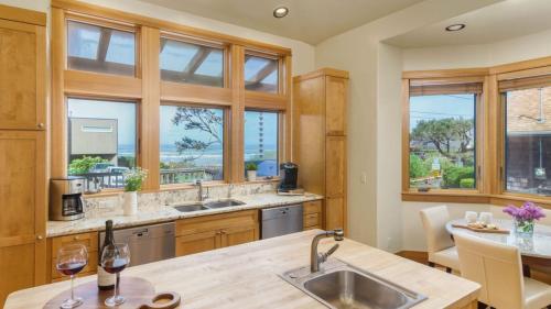 a kitchen with windows and a table with two wine glasses at The Castle Rock Estate by AvantStay Steps From Arch Cape beach w Hot Tub Sauna in Arch Cape