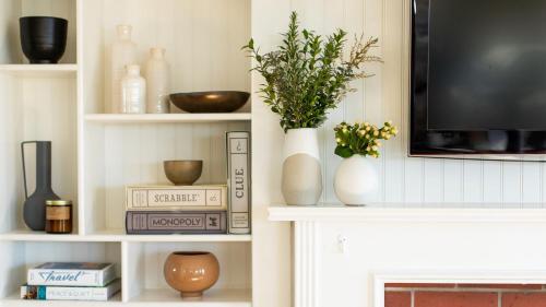 a living room with white shelves with vases and a tv at Kokomo by AvantStay Bayside Getaway w Fire Pit Large Outdoor Patio in San Diego