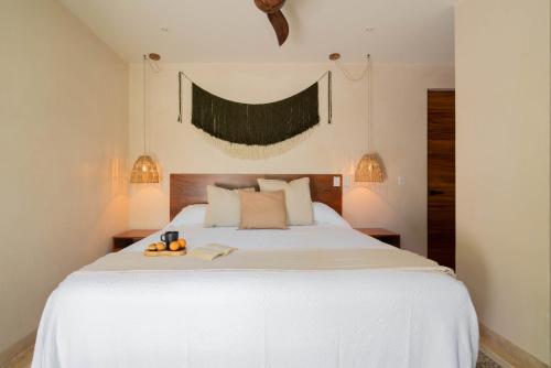 Chic Villa-Apartment in Aldea Zama, Private Pool & Security في تولوم: غرفة نوم بسرير ابيض كبير مع فواكه عليها