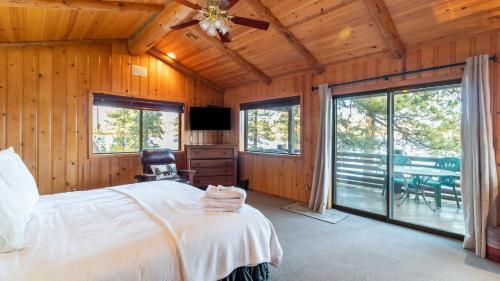 a bedroom with a bed and sliding glass doors at Shoreline Lakehouse by AvantStay Majestic Lakefront Cabin w Hot Tub Fire Pit in Big Bear Lake