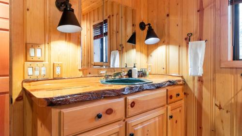 a wooden bathroom with a sink and a mirror at Shoreline Lakehouse by AvantStay Majestic Lakefront Cabin w Hot Tub Fire Pit in Big Bear Lake