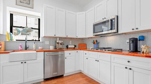 eine Küche mit weißen Schränken und einem Edelstahlkühlschrank in der Unterkunft Modern Chic Fishtown-Philly Home with Roof Deck in Philadelphia