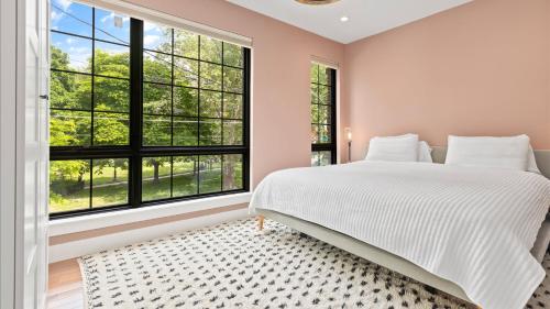 ein Schlafzimmer mit großem Bett und großen Fenstern in der Unterkunft Modern Chic Fishtown-Philly Home with Roof Deck in Philadelphia