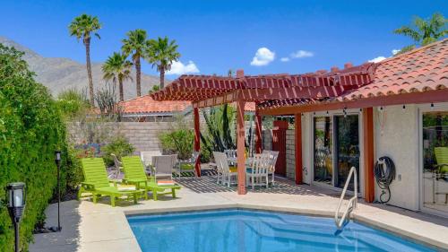 a house with a swimming pool and a patio with green chairs at Ranch Oasis w Private Pool HotTub Firepit Mountain Views Gobi by AvantStay in Palm Springs