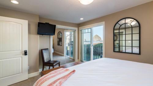 a bedroom with a bed and a chair and a window at Blue Starfish by AvantStay Ocean Views Direct Cannon Beach Access in Cannon Beach