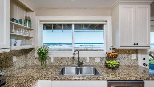 a kitchen with a sink and a window with the ocean at Blue Starfish by AvantStay Ocean Views Direct Cannon Beach Access in Cannon Beach