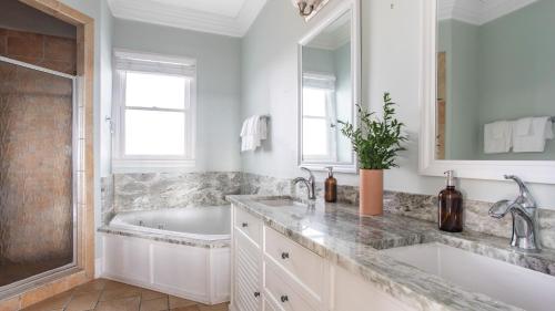 a white bathroom with a tub and a sink at Poseidon By AvantStay On The Beach Two Ocean Facing Balconies Hot Tub in Folly Beach
