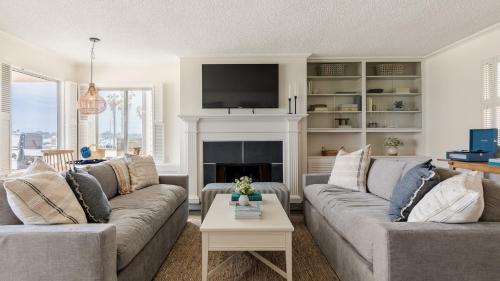 a living room with two couches and a fireplace at Bay View I by AvantStay Stylish Mission Beach Home on the Sand in San Diego