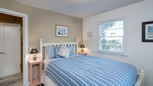 a bedroom with a bed with a blue comforter and a window at Beach Pines Bungalow by AvantStay Classic Cottage Steps to the Beach w Private Yard in Arch Cape