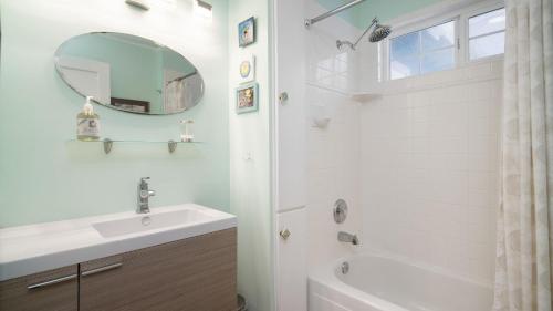 a white bathroom with a sink and a mirror at Beach Pines Bungalow by AvantStay Classic Cottage Steps to the Beach w Private Yard in Arch Cape