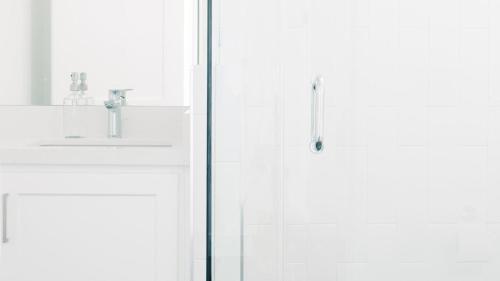 a white bathroom with a shower and a sink at ONeill I by AvantStay Coastal Paradise Steps from Beach Modern Decor in Newport Beach