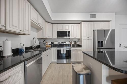 a kitchen with white cabinets and stainless steel appliances at Luxury Condo with Sanctuary Views Merritt Island in Audubon