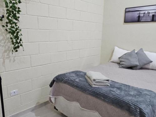 コチアにあるKitnet em Cotia perto Animalia Park CT do Sao Pauloのベッドとレンガの壁がある寝室