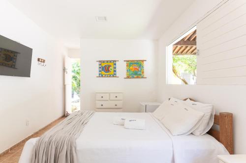 a white bedroom with a bed and a window at Casa a 100 metros do mar- no Centro de Porto de Galinhas in Porto De Galinhas