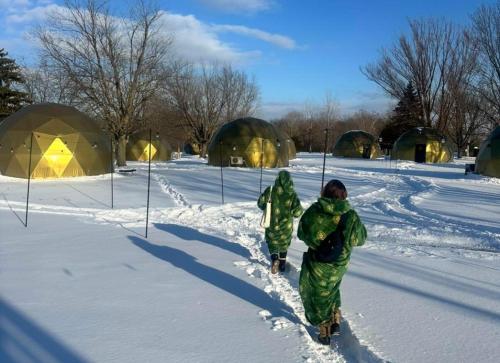 two people walking in the snow in front of tents at DayDreamer Domes in South Haven
