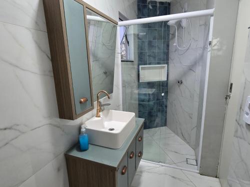 a white bathroom with a sink and a shower at Apartamento 8min da praia e 11 do Beto Carrero in Penha